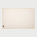 Vista frontal extendida del camino de mesa Cristina en color blanco roto o marfil; presenta una superficie rectangular de tela lisa con un distintivo borde perimetral en fibra natural de yute color arena.