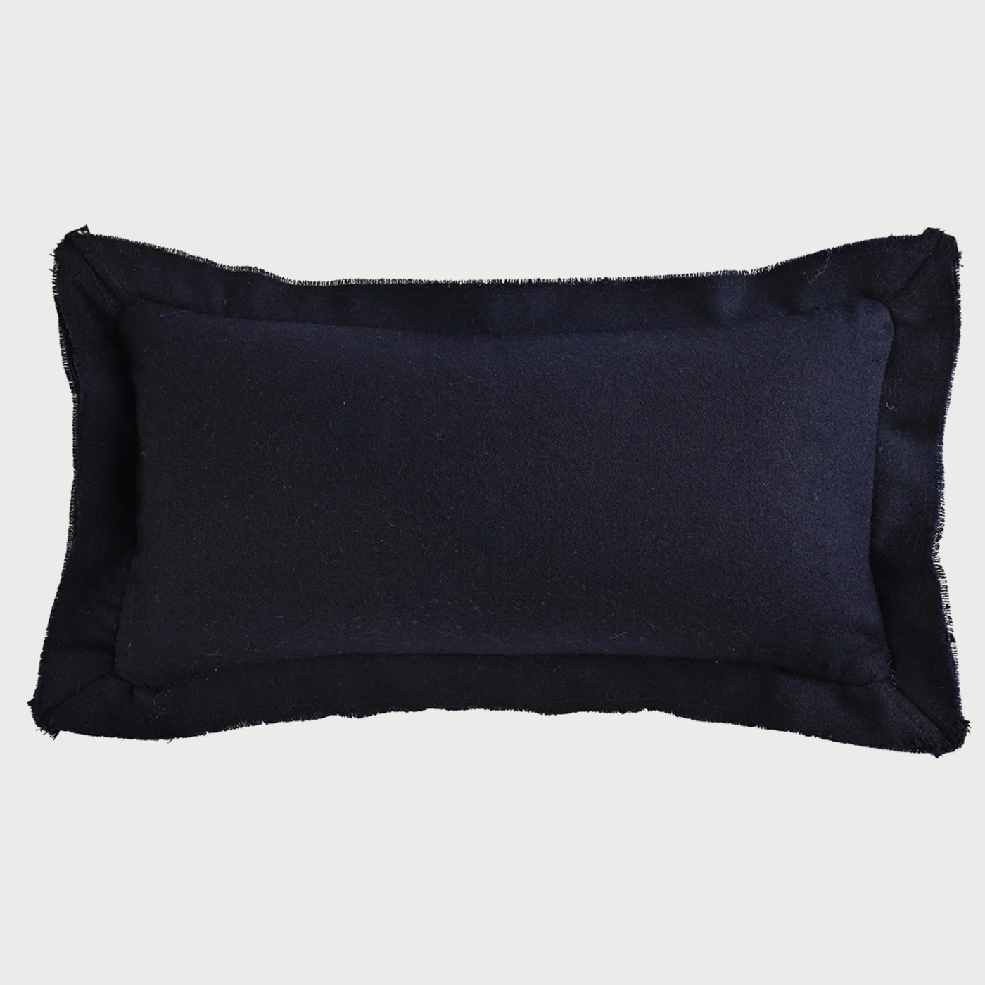 Vista frontal del cojín rectangular Céfiro de 30 x 50 cm en color azul marino; confeccionado en lana, destaca por su diseño de pestaña perimetral con bordes desflecados que aportan una textura rústica y acogedora.