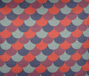 Acercamiento al textil del cojín Coto; se observa la trama del tejido con hilos entrelazados que dan cuerpo al patrón de escamas en tonos terracota, azul y gris, destacando la transición de color y la textura táctil de la superficie.