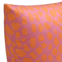 Acercamiento al textil del cojín Funk; muestra la superficie de terciopelo de tacto sedoso y el acabado nítido de las manchas naranja sobre el fondo rosa, resaltando la calidad de la impresión y la densidad del tejido.