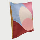 Vista lateral del cojín Ocaso; se aprecia su perfil con un relleno generoso que le otorga un volumen mullido y redondeado, resaltando la suavidad del textil de terciopelo y la transición de los colores vibrantes hacia los bordes.