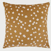 Vista frontal del cojín cuadrado Puntos de 50 x 50 cm; presenta un fondo de color ocre cálido decorado con un patrón irregular de motas o puntos blancos de bordes suaves, creando un efecto visual orgánico y acogedor similar a un estampado animal natural.
