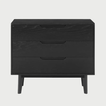 Vista frontal de la cómoda Talitha en color negro con tres cajones de frentes amplios, tiradores tipo uñero integrados y base de patas de madera cortas.