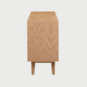Vista posterior de la cómoda Talitha en color beige, exhibiendo un panel de respaldo reforzado y la estructura estable de las patas de madera inclinadas.
