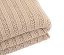 Frazada Gazia en color beige, doblada y con un patrón texturizado, perfecta para añadir calidez y estilo a tu hogar.