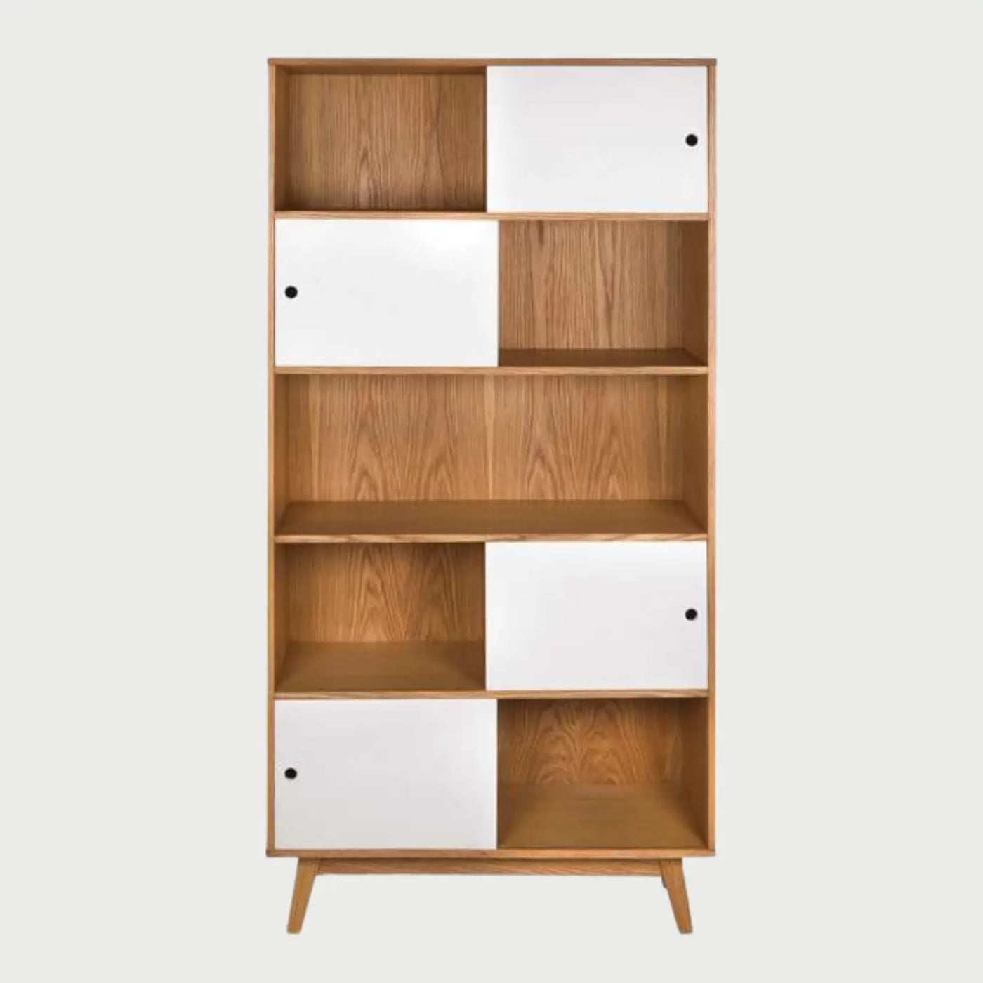 Vista frontal del librero Evo con estructura de madera clara y cinco niveles de repisas, con cuatro puertas blancas deslizantes distribuidas de forma asimétrica y tiradores circulares negros.