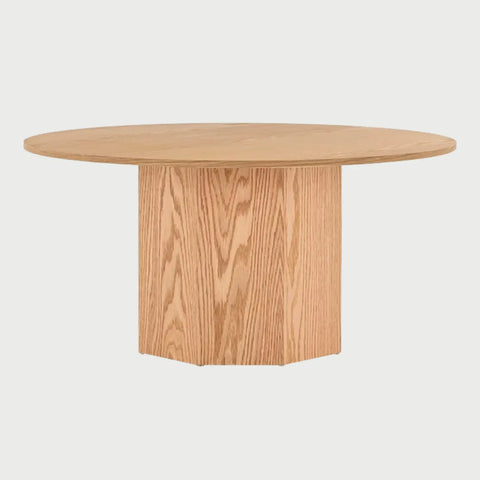 Vista frontal de la mesa de centro circular Aida en color beige encino; presenta una superficie redonda delgada soportada por una base cilíndrica central de gran volumen que muestra la veta natural de la madera.