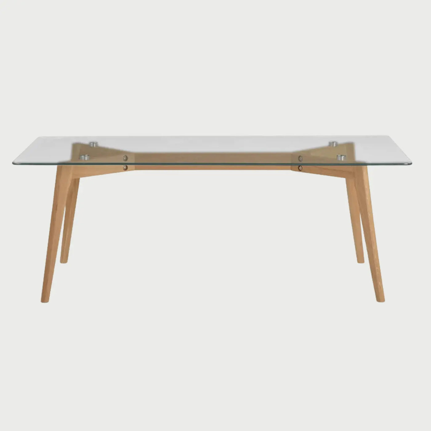 Vista frontal de la mesa de centro Ensemble; presenta una superficie rectangular de vidrio templado transparente y una base de madera de encino beige con patas angulares y soportes metálicos visibles.