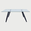 Vista frontal de la mesa de comedor Amit de 160 cm; presenta una superficie rectangular de cristal templado transparente apoyada sobre cuatro patas metálicas de color negro con diseño inclinado.