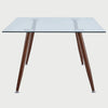 Vista frontal de la mesa de comedor Amit de 160 cm en variante café; mantiene la cubierta de cristal templado pero con patas metálicas en acabado madera nogal para un toque más cálido.