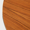 Acercamiento a la superficie circular de la mesa Loreta; destaca la veta horizontal de la madera en tono café nogal y el acabado liso del borde perimetral.