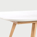 Acercamiento al lateral de la mesa de comedor Sei; se aprecia la unión entre la cubierta blanca de bordes redondeados y la estructura de soporte en madera de encino, resaltando el acabado liso y el diseño de líneas limpias.