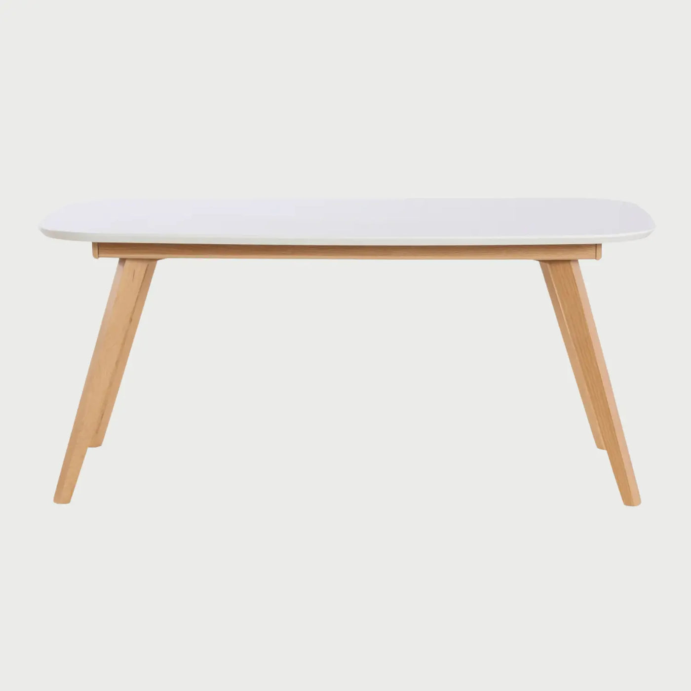 Vista frontal de la mesa de comedor Sei de 160 cm; presenta una superficie rectangular blanca con esquinas redondeadas y una base de cuatro patas angulares en madera clara de encino, combinando frescura y estabilidad.