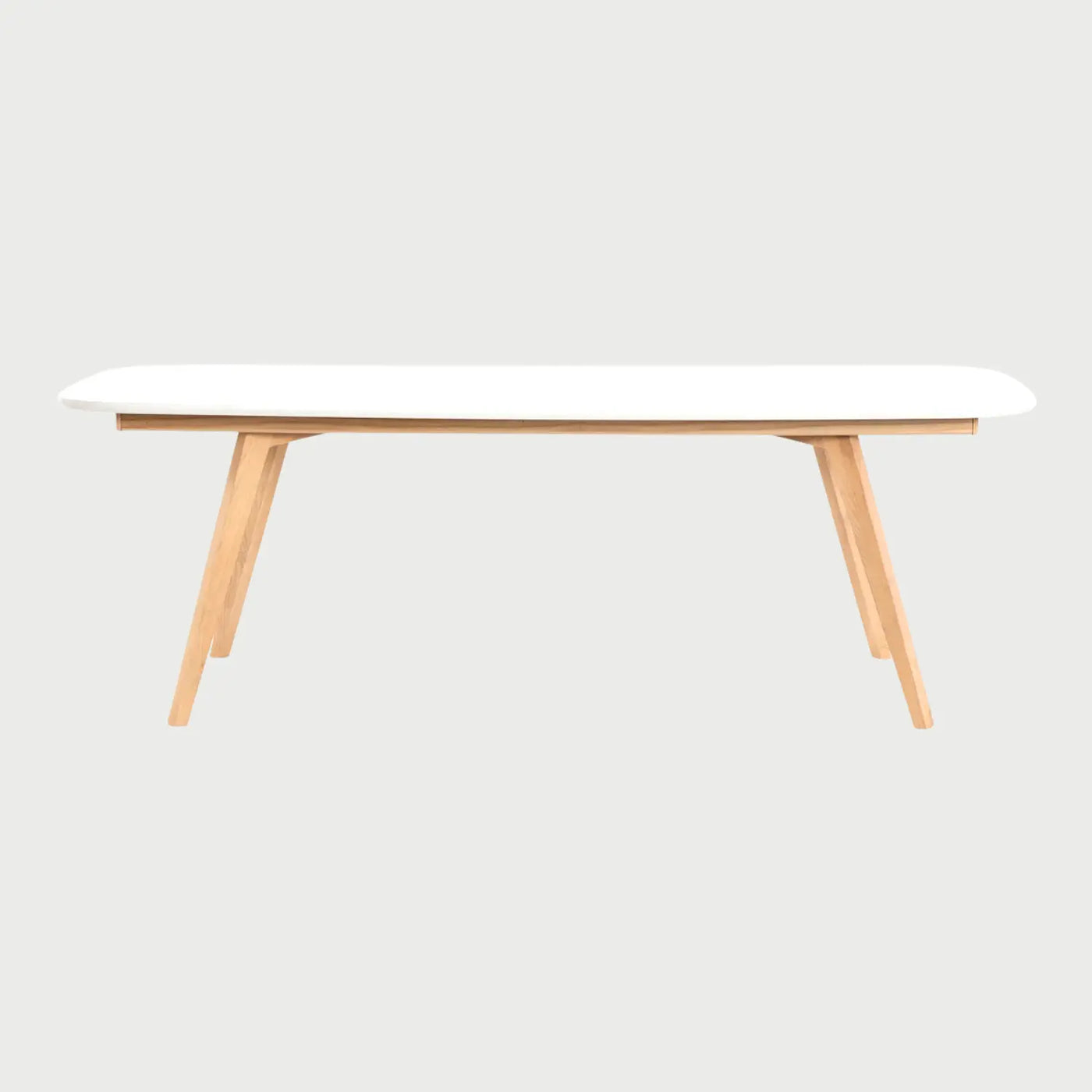 Vista frontal de la mesa de comedor Sei de 220 cm; presenta una superficie rectangular blanca con esquinas redondeadas y una base de madera clara con cuatro patas angulares que aportan estabilidad y un estilo nórdico moderno.