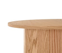 Mesa de centro Aida con superficie redonda y acabado en encino, mostrando una textura de madera natural y base cilíndrica.