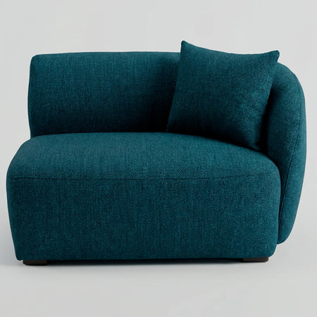 Vista frontal del módulo lateral Kant GAIA con brazo derecho en tela azul, destacando su diseño de líneas curvas, asiento profundo y un cojín decorativo a juego.