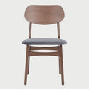 Vista frontal de la silla Boris con estructura de madera en acabado nogal oscuro y asiento acolchado tapizado en terciopelo gris; presenta un respaldo ancho y ergonómico de madera contrachapada.