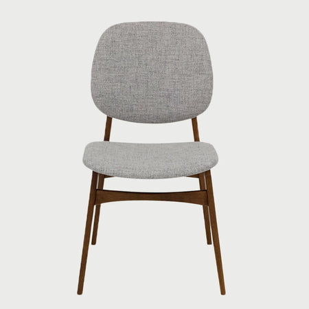Vista frontal de la silla de comedor Palmira, con asiento y respaldo redondeado tapizados en tela gris jaspeada y una estructura de patas de madera en acabado nogal oscuro con travesaños de refuerzo.
