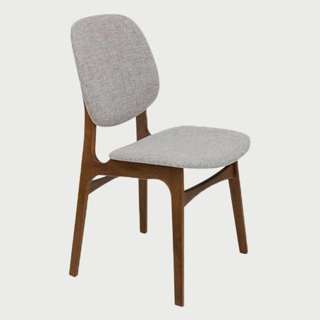 Vista lateral de la silla Palmira en color gris, mostrando el perfil ergonómico del respaldo separado del asiento y la inclinación de las patas de madera nogal que aportan un estilo moderno de mediados de siglo.