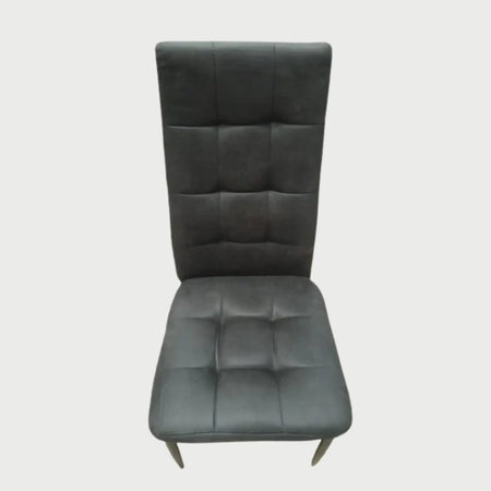 Vista frontal de la silla de comedor Sian tapizada en tela color gris oscuro, con un diseño capitonado de cuadros costurados en el respaldo alto y el asiento, sobre patas delgadas.