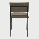 Vista posterior de la silla Soma en color verde, exhibiendo la parte trasera del respaldo tapizado y la continuidad de la estructura metálica negra que sostiene la pieza.