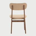 Vista posterior de la silla Marcela, exhibiendo la veta de la madera en el respaldo ovalado y la construcción limpia de la base en acabado nogal.