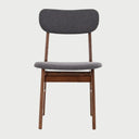 Vista frontal de la silla Marcela en color gris, destacando el contraste sofisticado entre el tejido neutro y la profundidad del acabado nogal en las patas y el respaldo.