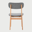 Vista posterior de la silla Marcela, exhibiendo la veta natural de la madera en el reverso del respaldo y la construcción limpia de las patas traseras en tono encino claro.