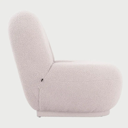 Vista lateral del sillón Toscana GAIA en tejido boucle blanco, destacando su silueta orgánica con base totalmente tapizada, respaldo curvo y asiento profundo de estilo contemporáneo.