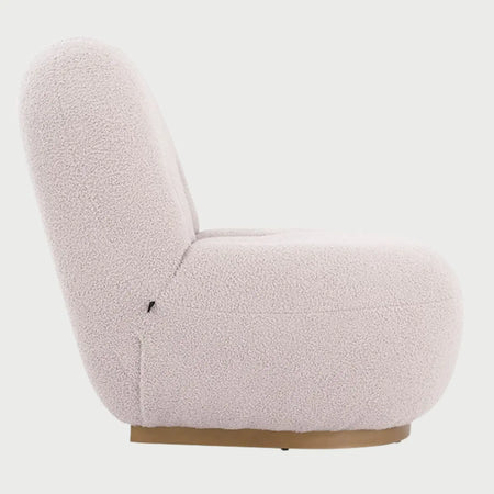 Vista lateral del sillón Toscana GAIA en tejido boucle blanco, mostrando su diseño orgánico de líneas curvas y una base de madera circular que aporta un toque cálido y moderno.