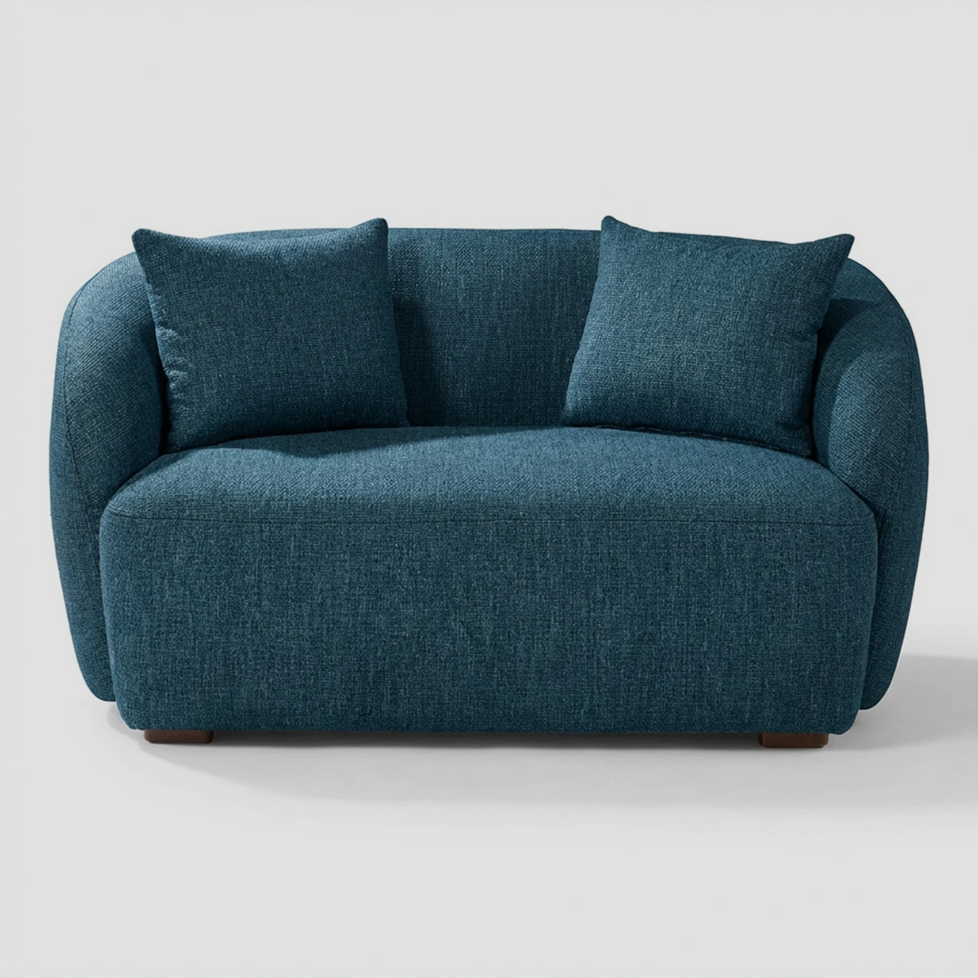 Vista frontal del sillón XL Kant GAIA en tela azul, que muestra su diseño de dos plazas con formas redondeadas, brazos integrados envolventes y dos cojines decorativos rectangulares a juego.