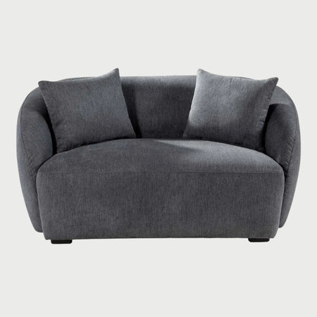 Vista frontal del sillón XL Kant en tono gris oscuro, resaltando el contraste de sus formas redondeadas con el tejido de textura densa y sus patas bajas discretas.