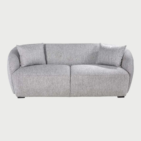 Vista frontal del sofá Kant de dos cuerpos en color gris, resaltando su silueta baja y contemporánea con cojines de respaldo mullidos y un diseño de base sólida.