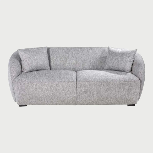 Vista frontal del sofá Kant de dos cuerpos en color gris, resaltando su silueta baja y contemporánea con cojines de respaldo mullidos y un diseño de base sólida.