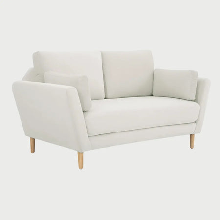 Vista lateral del sofá de dos cuerpos Levanto GAIA en tela blanca, mostrando el perfil recto de los brazos, el acolchado del asiento y el soporte de las patas de madera clara en acabado encino.
