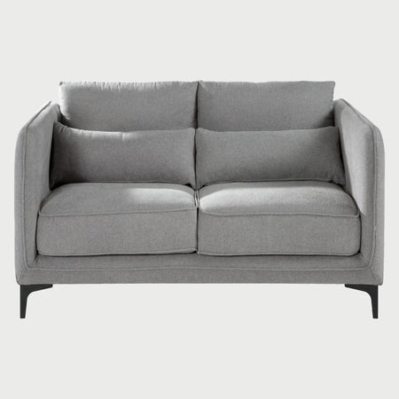 Vista frontal del sofá Marina de dos cuerpos en tela gris claro, mostrando el equilibrio entre sus formas suaves y sus patas metálicas minimalistas.