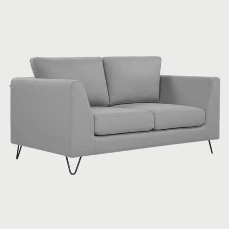 Vista de perfil del sofá de dos cuerpos Yoco GAIA en tela gris, mostrando los brazos angulados hacia afuera y el soporte de las patas metálicas tipo hairpin en color negro.