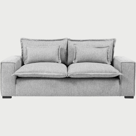 Vista frontal del sofá Emilia GAIA de tres cuerpos en tela color gris, destacando sus asientos de gran formato, cojines de respaldo dobles superpuestos y brazos rectos que acentúan su diseño moderno y acogedor.