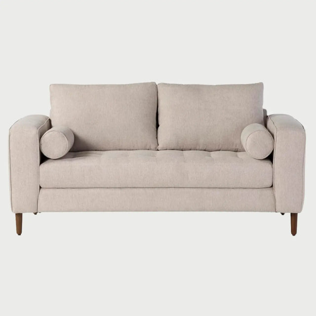 Sofá de tres cuerpos Landero GAIA tapizado en tela beige con asiento capitonado, cojines cilíndricos laterales y patas de madera delgadas.