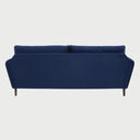 Vista posterior del sofá Levanto de tres cuerpos en azul, mostrando un acabado de tapicería liso y continuo con la estructura elevada sobre patas de madera oscura.