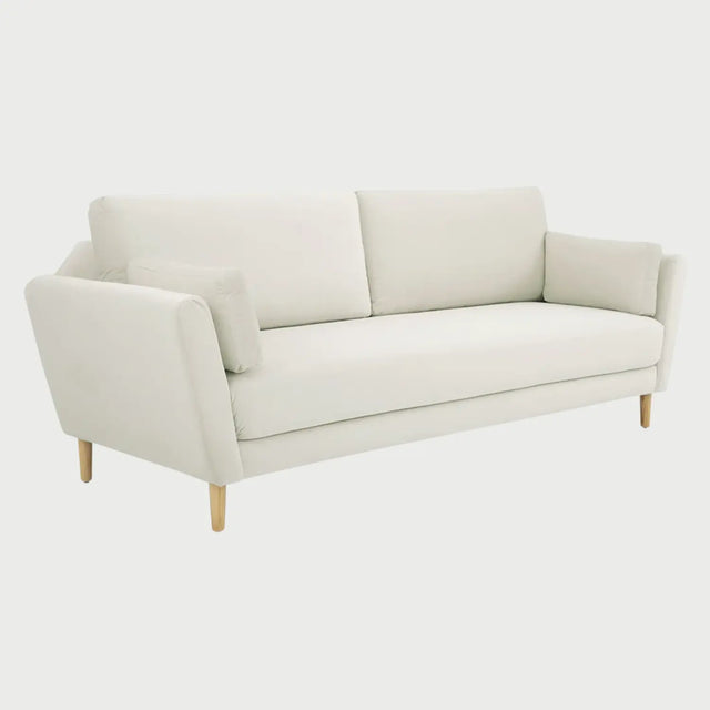 Vista lateral del sofá Levanto blanco, resaltando la inclinación hacia afuera de los descansabrazos y el diseño cónico de las patas de madera de encino que aportan un estilo escandinavo.