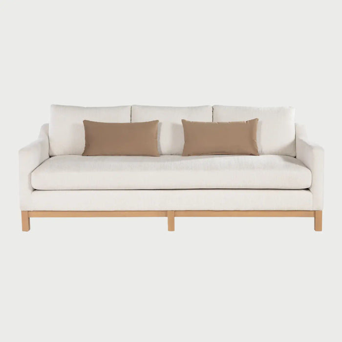 Vista frontal del sofá Mar de tres cuerpos en color blanco, destacando el contraste entre el textil claro y la base de madera natural, manteniendo su silueta elegante y minimalista.