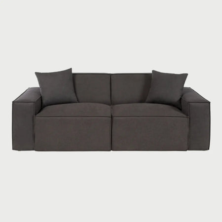 Vista frontal del sofá Otto de tres cuerpos en gris oscuro, resaltando su apariencia imponente y sofisticada con asientos profundos y una estructura de bloques que invita al descanso.