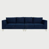 Vista frontal del sofá Yoco de cuatro plazas tapizado en terciopelo azul marino, con cuatro cojines de respaldo y asiento individuales, elevado sobre elegantes patas metálicas tipo horquilla en acabado dorado.