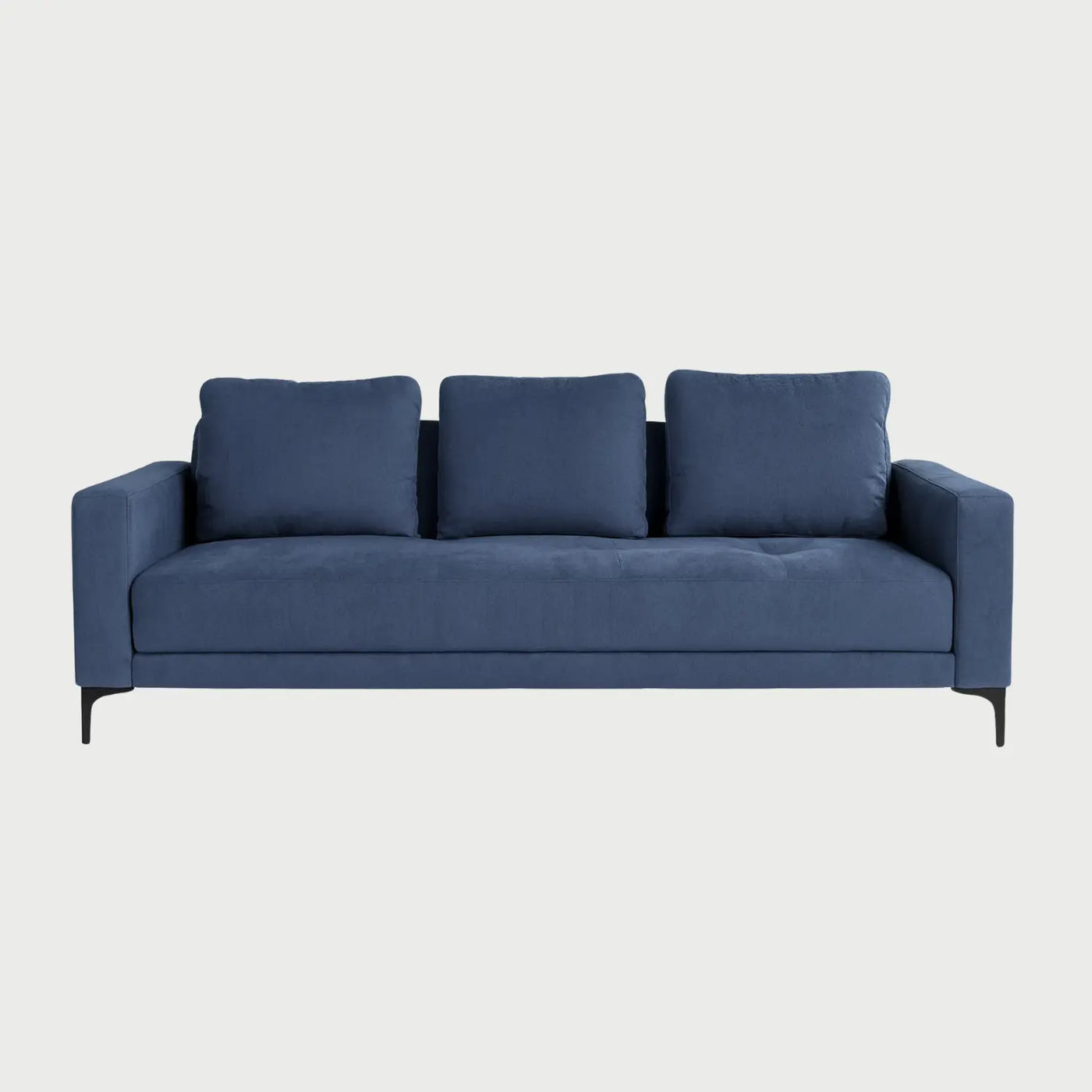 Vista frontal del sofá cama Arriaga tapizado en tela color azul, con tres cojines de respaldo rectangulares y base elevada sobre patas metálicas negras esbeltas.