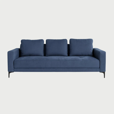 Vista frontal del sofá cama Arriaga tapizado en tela color azul, con tres cojines de respaldo rectangulares y base elevada sobre patas metálicas negras esbeltas.