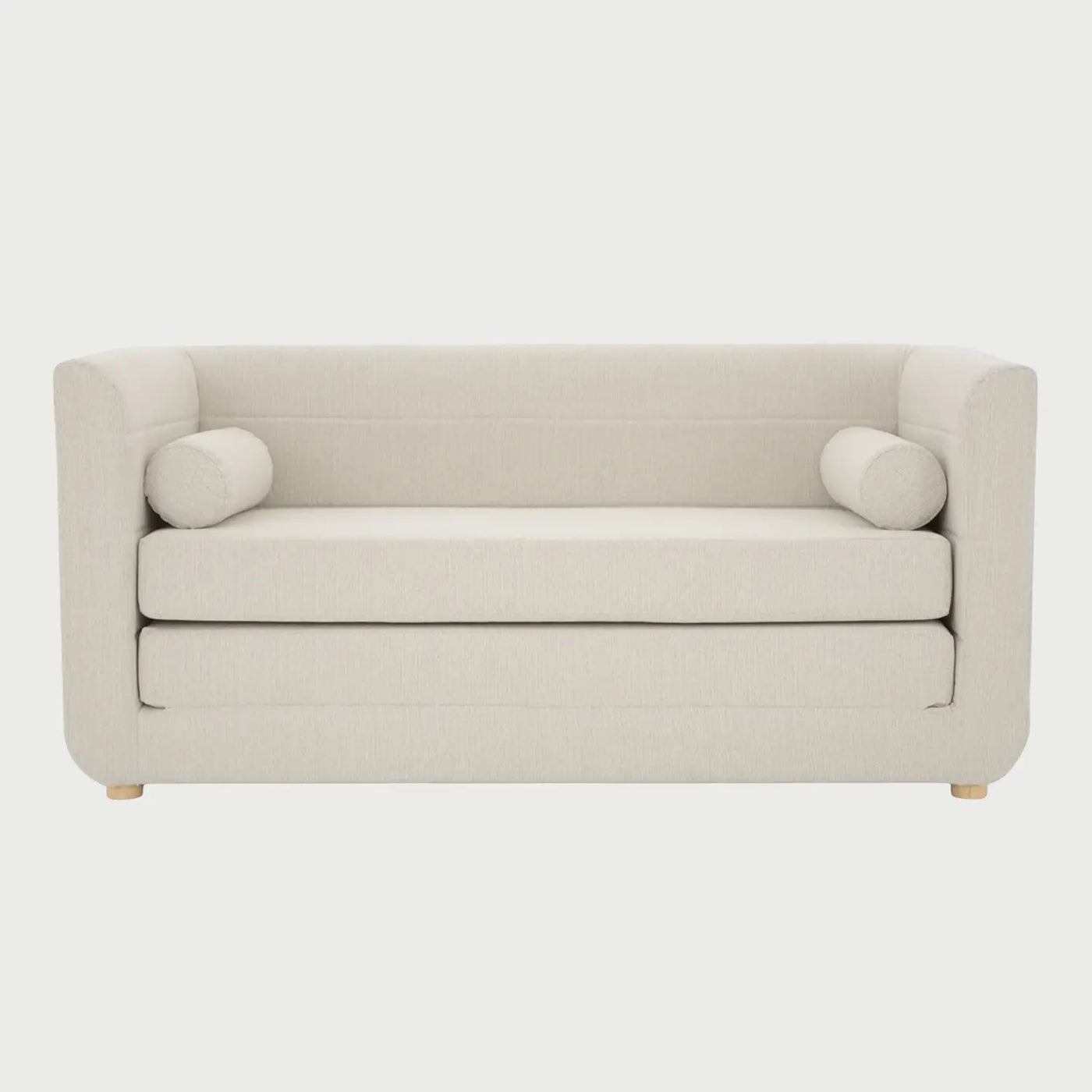 Vista frontal del sofá cama Basil en color blanco, con diseño de respaldo bajo, asiento de doble capa y patas de madera natural con acabado barnizado.