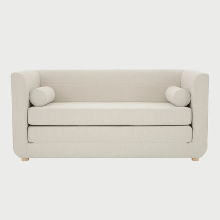 Vista frontal del sofá cama Basil en color blanco, con diseño de respaldo bajo, asiento de doble capa y patas de madera natural con acabado barnizado.