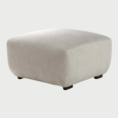 Vista frontal del taburete Kant en color blanco, destacando su diseño limpio y contemporáneo con patas cortas oscuras que elevan sutilmente el cuerpo volumétrico de la pieza.