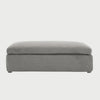 Vista frontal del taburete Marie en color gris, con un diseño rectangular alargado, cojín superior de gran espesor y base tapizada liza que llega casi al nivel del suelo.